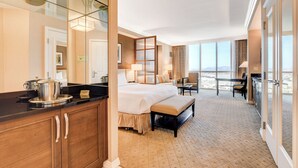 Une chambre d’hôtel dotée d’un grand lit, d’un coin repas, d’une cuisine et d’un balcon avec vue.