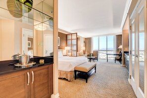 Ein Hotelzimmer mit einem großen Bett, einer Essecke, einer Küche und einem Balkon mit Blick.