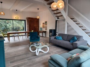 A modern living room with a glass coffee table, a sofa, and a dining area with chairs and a table. - Family home between the beaches and Cap Fréhel (Plévenon)