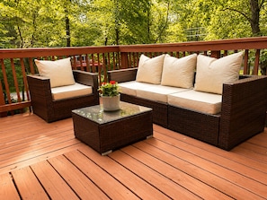 Eine Terrasse mit Korbmöbeln, darunter eine Sitzecke mit Sofa und Stühlen, sowie ein kleiner Tisch mit Blumenvase.