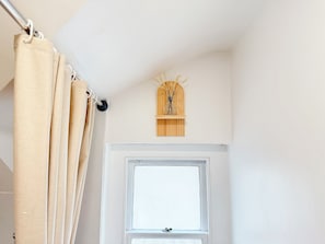 A bathroom with a window, a curtain, and a wall-mounted shelf with a decorative item. - Prime City of London Accomodation in St Paul’s, Bank, Liverpool Street for (London)