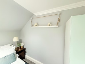 A bedroom with a bed, bedside table, lamp, and a shelf with decorative items. - Prime City of London Accomodation in St Paul’s, Bank, Liverpool Street for (London)