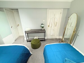 Een slaapkamer met twee bedden, een bureau, een spiegel en een kledingkast.