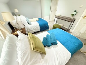 A hotel room with two beds, each with a blue and white bedspread, and a small table with a vase of flowers. - Prime City of London Accomodation in St Paul’s, Bank, Liverpool Street for (London)