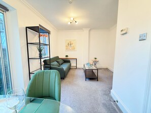 A living room with a green sofa, a glass coffee table, a bookshelf, and a small side table with a plant. - Prime City of London Accomodation in St Paul’s, Bank, Liverpool Street for (London)