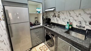 A modern kitchen with stainless steel appliances, a built-in oven, a gas stove, and a sink. - Modern Apartment with Wi-Fi and Air Conditioning, Near the Beach and the Medina (Tanger)