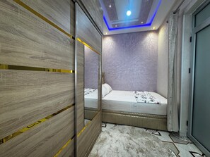 A bedroom with a bed, a mirror, and a ceiling light. - Modern Apartment with Wi-Fi and Air Conditioning, Near the Beach and the Medina (Tanger)