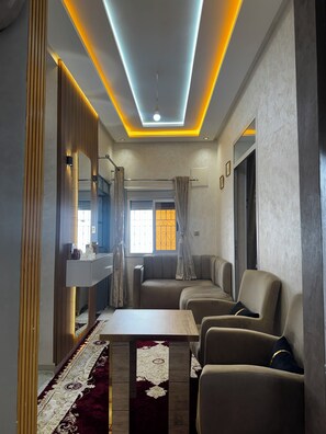 A modern living room with a sofa, a coffee table, and a mirror. - Modern Apartment with Wi-Fi and Air Conditioning, Near the Beach and the Medina (Tanger)