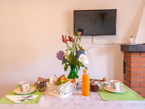 Desayuno preparado con un jarrón de flores, una botella de jugo de naranja y un televisor de pantalla plana montado en la pared.