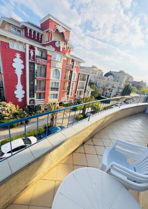 A balcony with outdoor seating, a decorative railing, and a view of a multi-story building with balconies. - Serene 1-bedroom apartment with 2 AC in sunny Sunny Beach, 5 min to the beach (Sunny Beach)