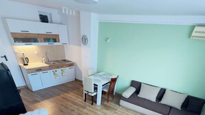 Ett modernt vardagsrum med en soffa, ett matbord och ett litet kök.