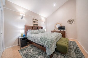 A bedroom with a bed, bedside tables, a dresser, a television, and decorative wall art. - Lake Conroe Luxury Retreat - Boat Slip & Sunsets (Montgomery)