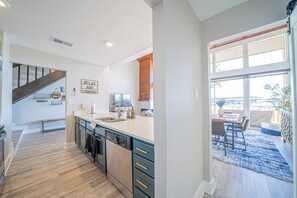 A modern kitchen with a central island, wooden flooring, and a dining area with a view. - Lake Conroe Luxury Retreat - Boat Slip & Sunsets (Montgomery)