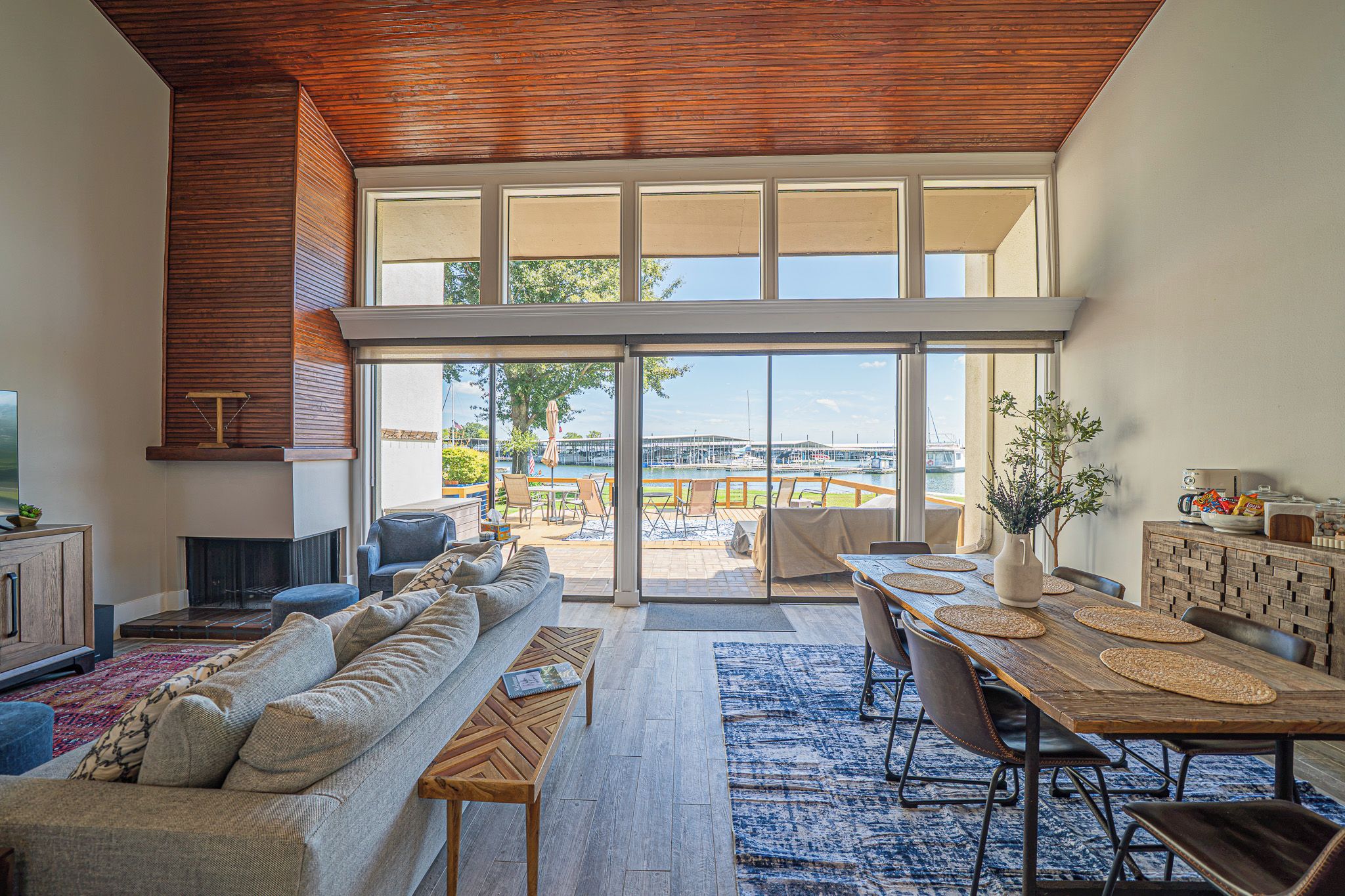 Een ruime woonkamer met een grote schuifpui die uitkomt op een balkon met uitzicht op een jachthaven.