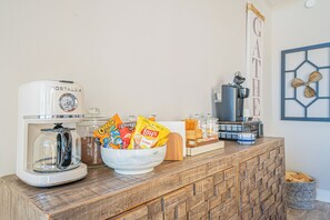 A kitchenette with a coffee maker, a bowl of snacks, a coffee machine, and a decorative wall piece. - Lake Conroe Luxury Retreat - Boat Slip & Sunsets (Montgomery)