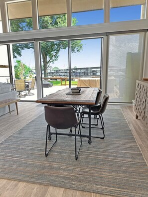 A modern dining area with a large table, chairs, and a view of a marina. - Lake Conroe, waterfront, boat dock, pets welcome (Montgomery)