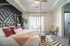 Une chambre à coucher moderne avec un lit, un ventilateur de plafond, une fenêtre, une plante et un banc.