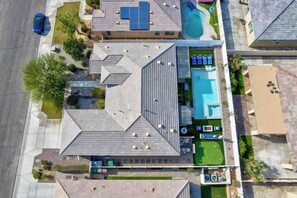 An aerial view of a residential property with a swimming pool, solar panels, and a well-maintained lawn. - Golden Hour - Pool, Spa, BBQ, Mini-Golf, Gameroom! (Indio)