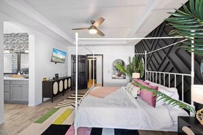 A modern bedroom with a bed, a ceiling fan, and a view into the bathroom. - Golden Hour - Pool, Spa, BBQ, Mini-Golf, Gameroom! (Indio)
