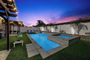 Un jardin avec une piscine, un espace barbecue et un coin salon abrité.