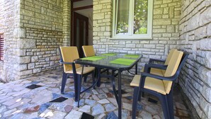 Een terras met stenen muren, een tafel en vier stoelen.