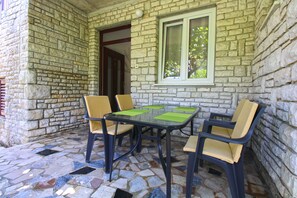 A stone-walled outdoor seating area with a table and four chairs. - Apartment 2450/264997 (Istria - Fažana), 300m from the beach (Fažana)