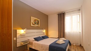 Een slaapkamer met een bed, nachtlampen, een schilderij en een raam met gordijnen.