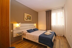 A bedroom with a bed, bedside lamps, a painting, and a window with curtains. - Apartment 2450/264997 (Istria - Fažana), 300m from the beach (Fažana)