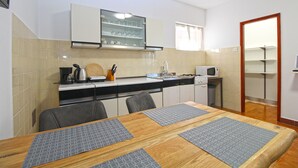 A compact kitchen with a dining table, chairs, and basic appliances. - Apartment 2450/264998 (Istria - Fažana), 300m from the beach (Fažana)