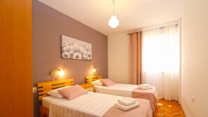 A hotel room with two beds, a painting on the wall, and a window with curtains. - Apartment 2450/264998 (Istria - Fažana), 300m from the beach (Fažana)