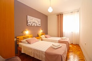 Ein Hotelzimmer mit zwei Betten, einem Bild an der Wand und einem Fenster mit Vorhängen.