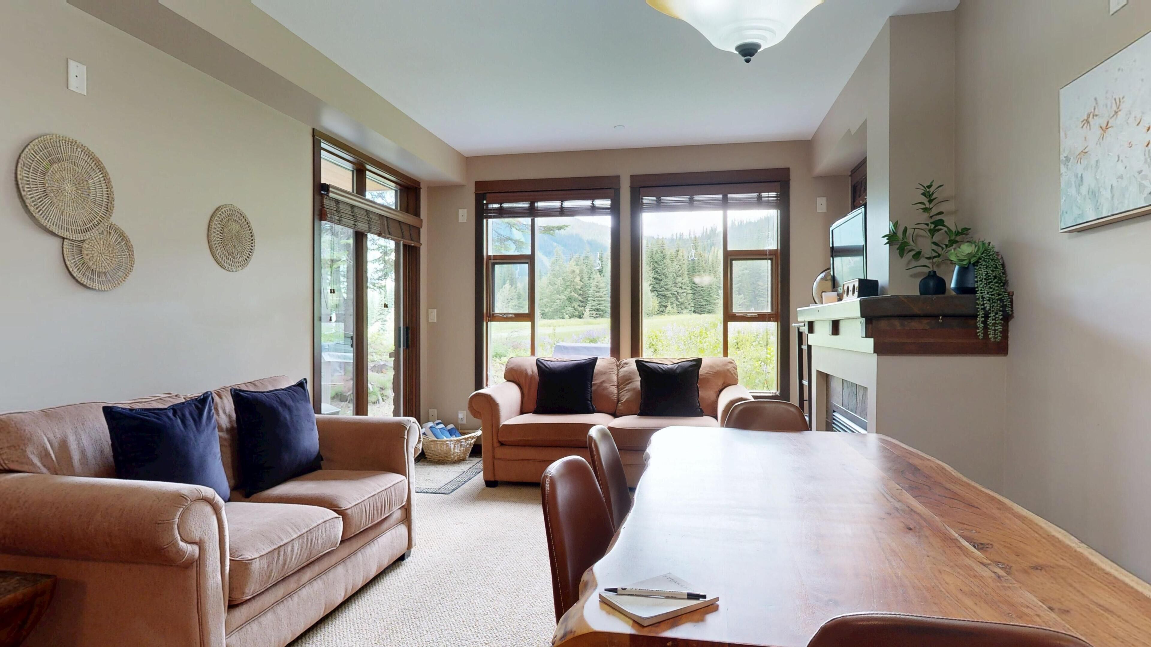 A living room with a large wooden table, two sofas, and a fireplace.