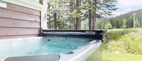 A hot tub with a view of a forest and a ski lift in the background.