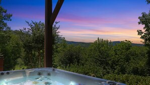 A hot tub with a view of a forest and mountains.