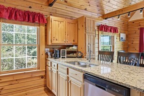 A wooden cabin interior with a kitchen featuring granite countertops, wooden cabinets, a coffee machine, and a dishwasher. - Gorgeous mountain views~Sunsets~Hot Tub~Fire Pit (Bostic)