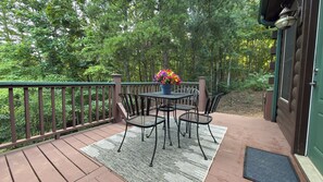 A deck with a table and chairs, surrounded by a wooden railing, and a potted plant with flowers.