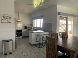 A kitchen with a central island, bar stools, a dining table, and a view through a window. - Comfy 4 Bedroom with country views (Atherton)