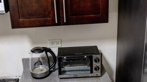 A kitchen with a coffee maker, a toaster oven, and wooden cabinets. - Beyond Escape-2br-gated-15 Min to Ocho Rios (Boscobel)