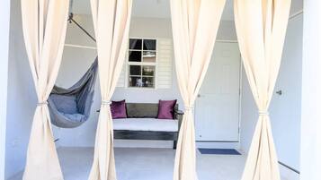 A room with a bed, a hanging chair, and beige curtains.