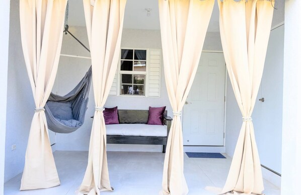 A room with a bed, a hanging chair, and beige curtains. - Beyond Escape-2br-gated-15 Min to Ocho Rios (Boscobel)