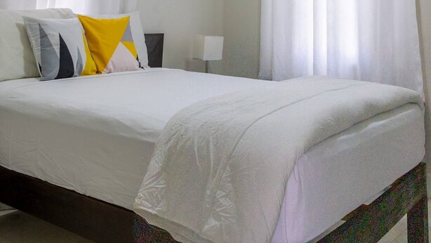 A bedroom with a bed, white curtains, a ceiling fan, and an air conditioning unit. - Beyond Escape-2br-gated-15 Min to Ocho Rios (Boscobel)
