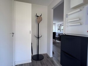 A hallway with a coat rack, a door, and a black appliance, possibly a refrigerator. - 5 Star Holiday Home in Uddevalla (Uddevalla)