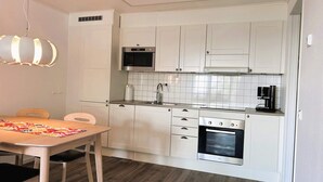 A compact kitchen with white cabinetry, a microwave, a coffee maker, and a built-in oven. - 5 Star Holiday Home in Uddevalla (Uddevalla)