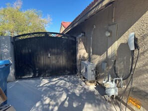 A gated entrance with a metal gate, a concrete floor, and a building with a textured wall and a red-tiled roof. - Cozy & Modern Studio near Strip, Freemont & LVCC. Free Parking & Private Patio. (Las Vegas)