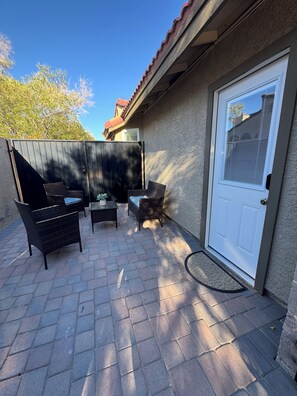 A patio with outdoor furniture, a door, and a wall. - Cozy & Modern Studio near Strip, Freemont & LVCC. Free Parking & Private Patio. (Las Vegas)