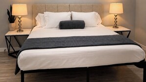 Un dormitorio con una cama, dos mesitas de noche con lámparas, un ventilador de techo y una luminaria.