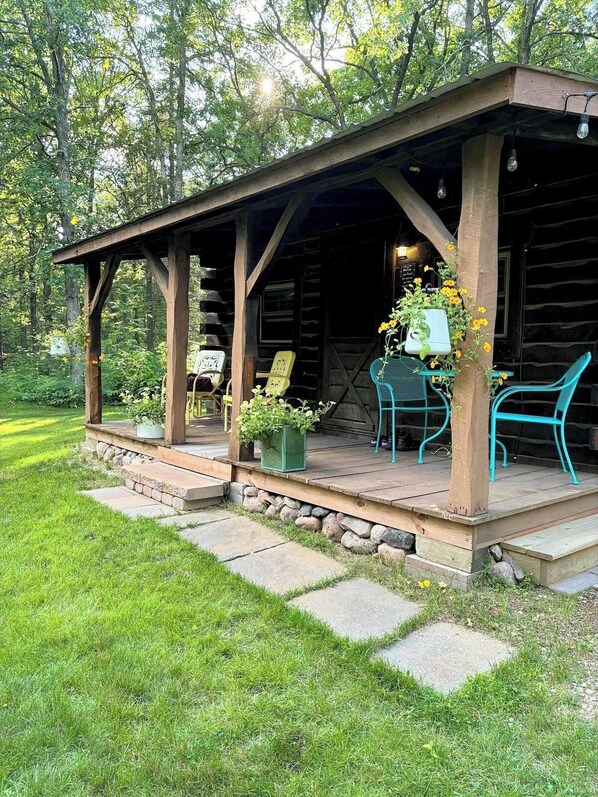 Une cabane en bois avec un porche, des marches en pierre et un espace salon extérieur.