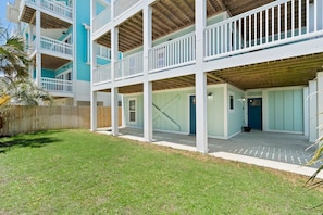 A multi-story building with balconies, a covered patio area, and a fenced yard. - Luxury Ocean View Home w Pool Access, Rooftop, and Pool Table! (Carolina Beach)