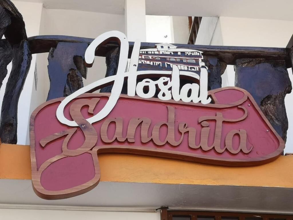 A sign with the text 'Hostal Sandrita' on a building facade.