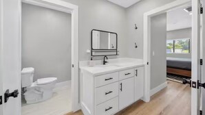 Un baño moderno con un tocador blanco, un espejo y un inodoro.